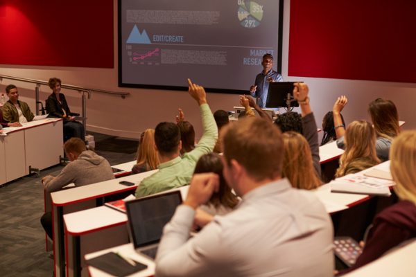 Students at university lecture raise hands to ask questions