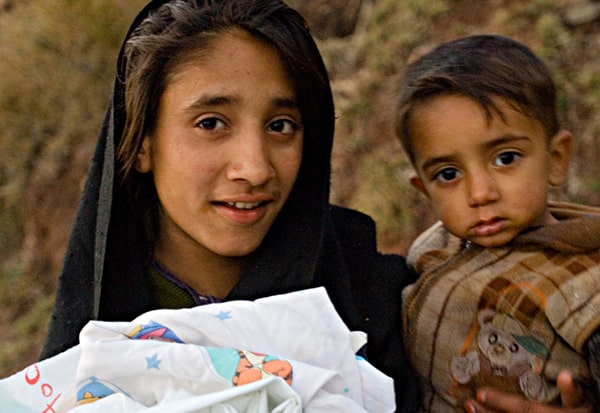Girl holding toddler and humanitarian aid