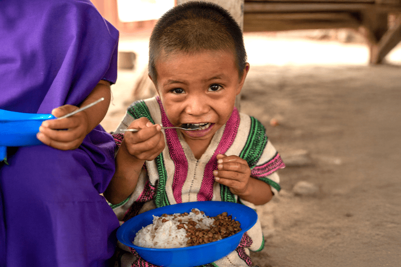 little boy eating rice and beans